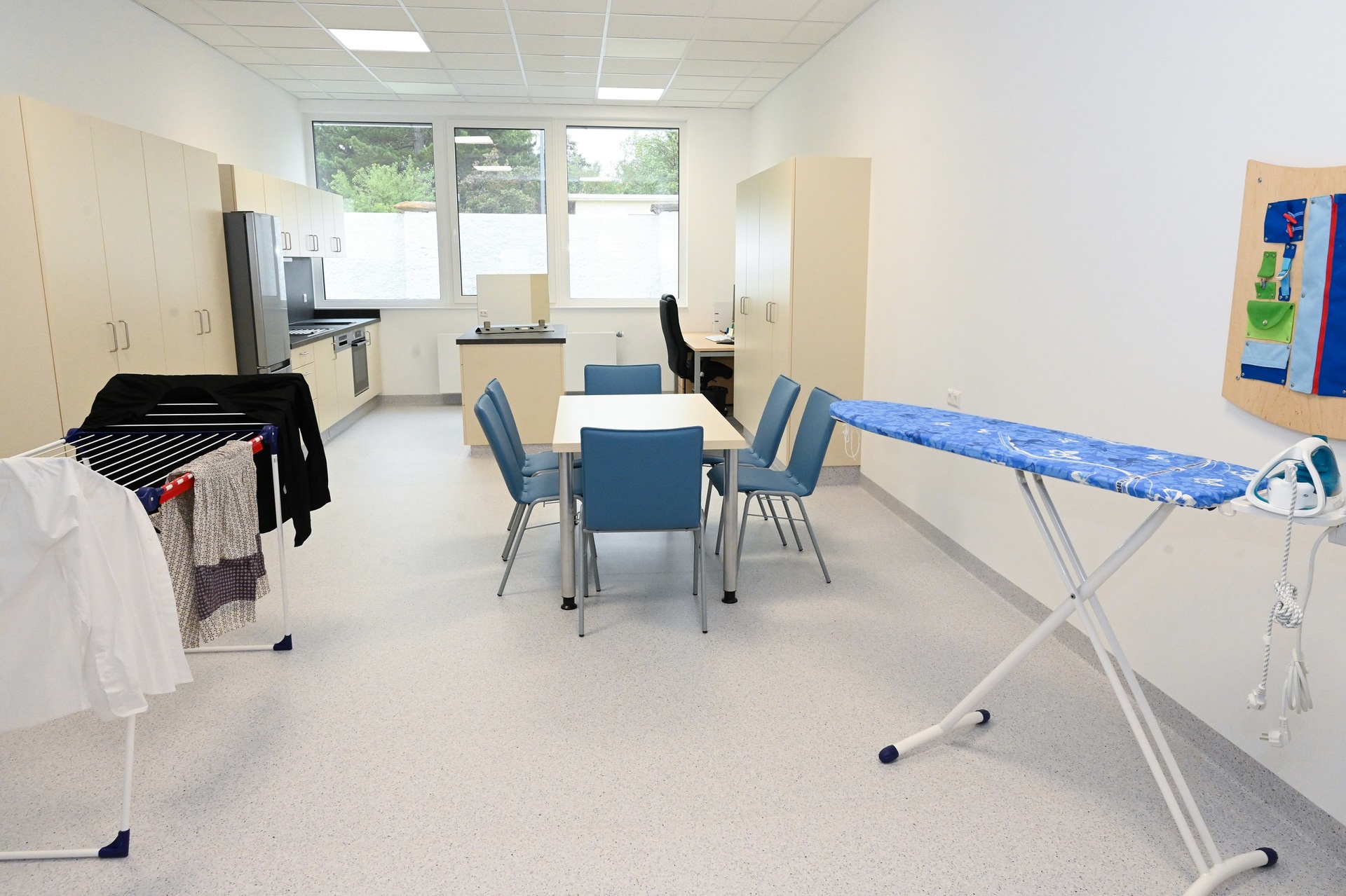 Raum mit Wäscheständer, Bügeltisch und Tisch mit mehreren Stühlen