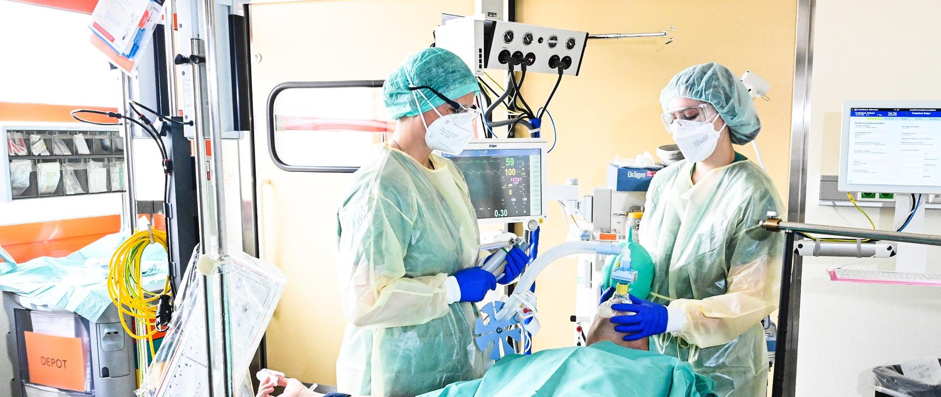 Intensivstation: Zwei Pflegerinnen versorgen einen Patienten der an Geräte angeschlossen ist